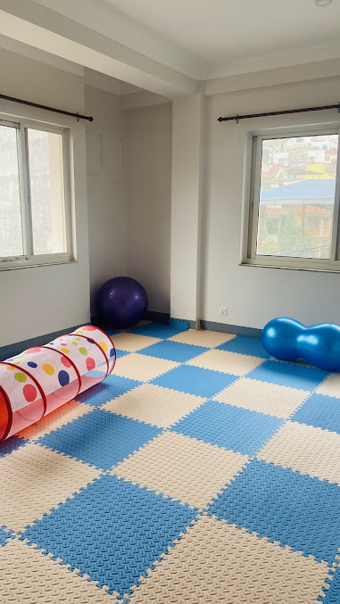 Open therapy floor with exercise balls and soft mat area